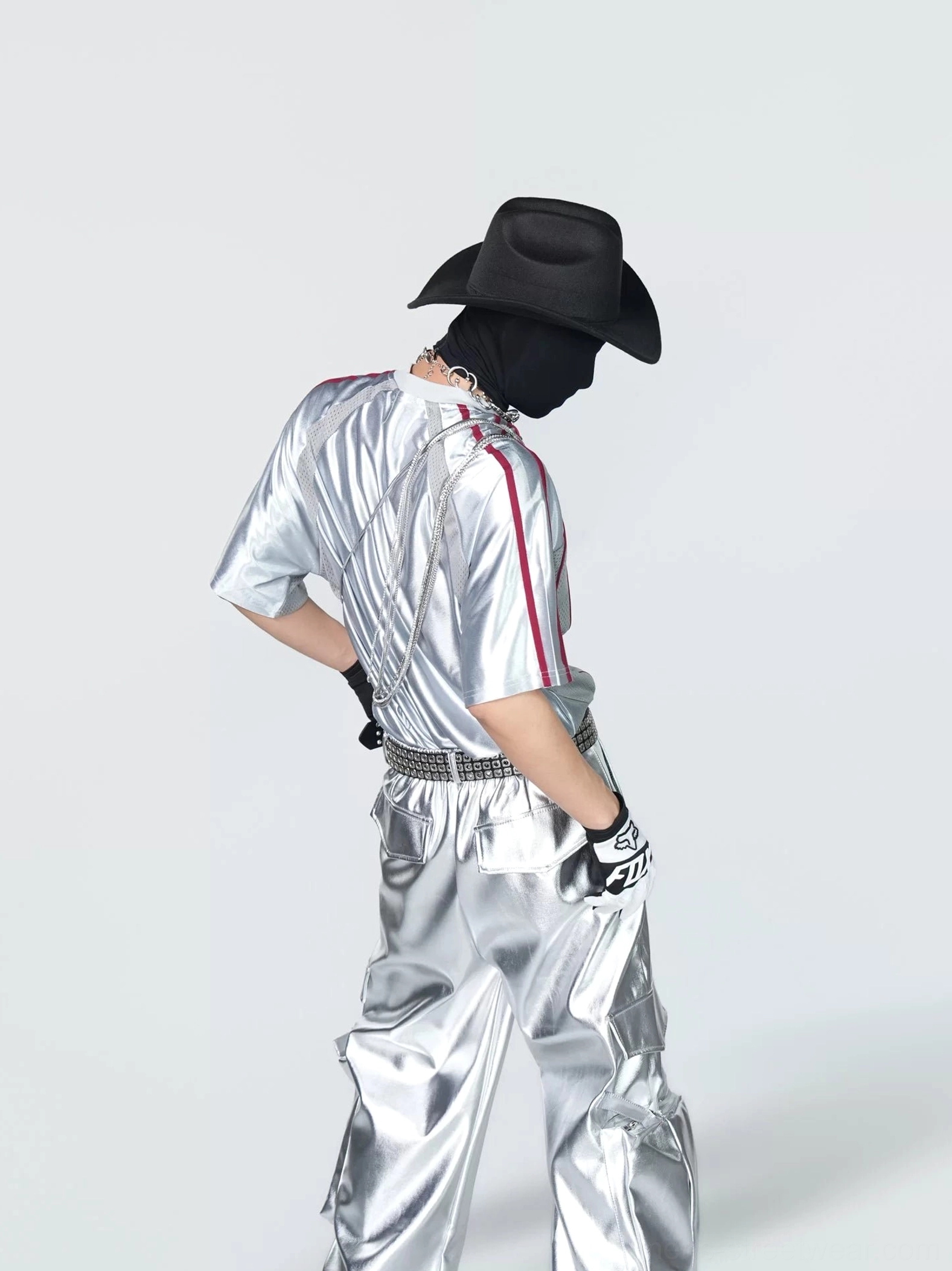 Back three-quarter view of a glossy silver short-sleeve tech jersey with red sleeve trim and futuristic Korean streetwear styling