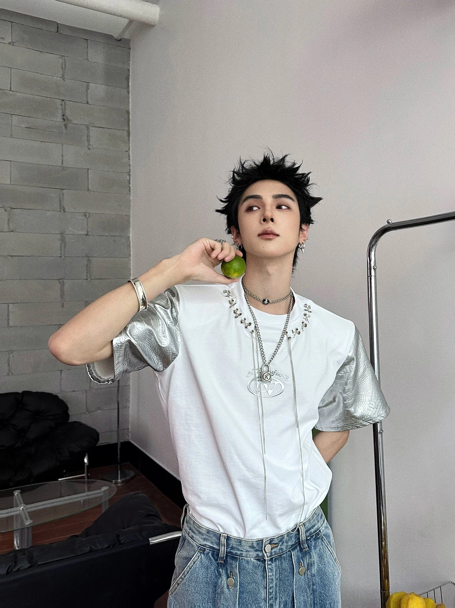 White and silver metallic sleeve chain lace panel T-shirt styled with blue jeans and layered necklaces in a minimalist indoor setting