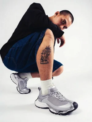 Metallic split-toe technical runner sneakers worn with white crew socks, black top, and denim shorts in a Korean streetwear studio outfit
