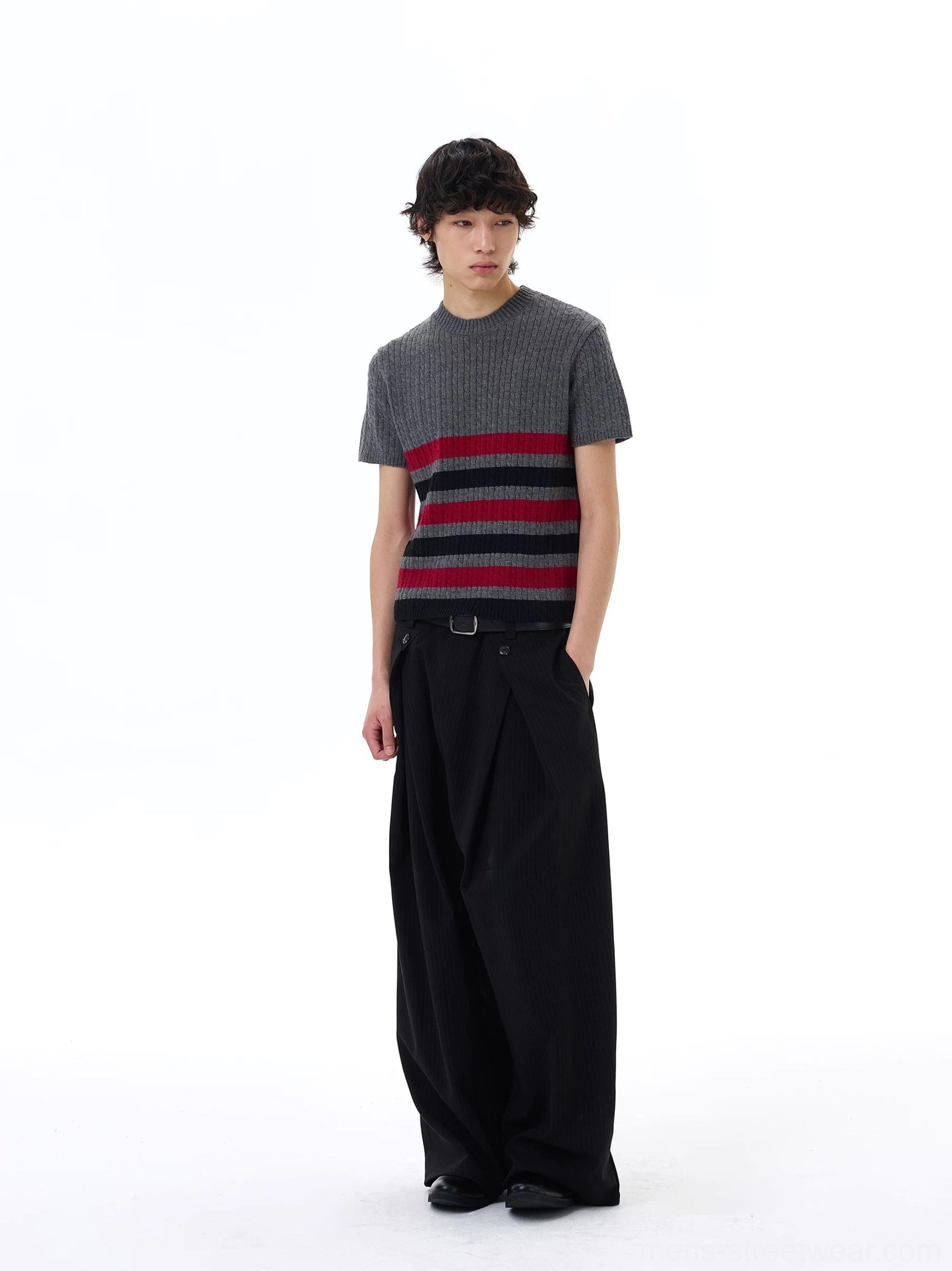 Three-quarter side view of a grey striped ribbed knit short sleeve tee paired with loose black trousers