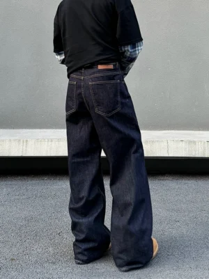Rear view of dark indigo men’s wide-leg denim jeans with roomy stacked fit, back patch pockets, and leather waist tab