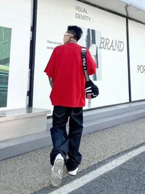 Back view of midnight fade relaxed straight leg dark indigo jeans styled with oversized red t shirt and crossbody bag
