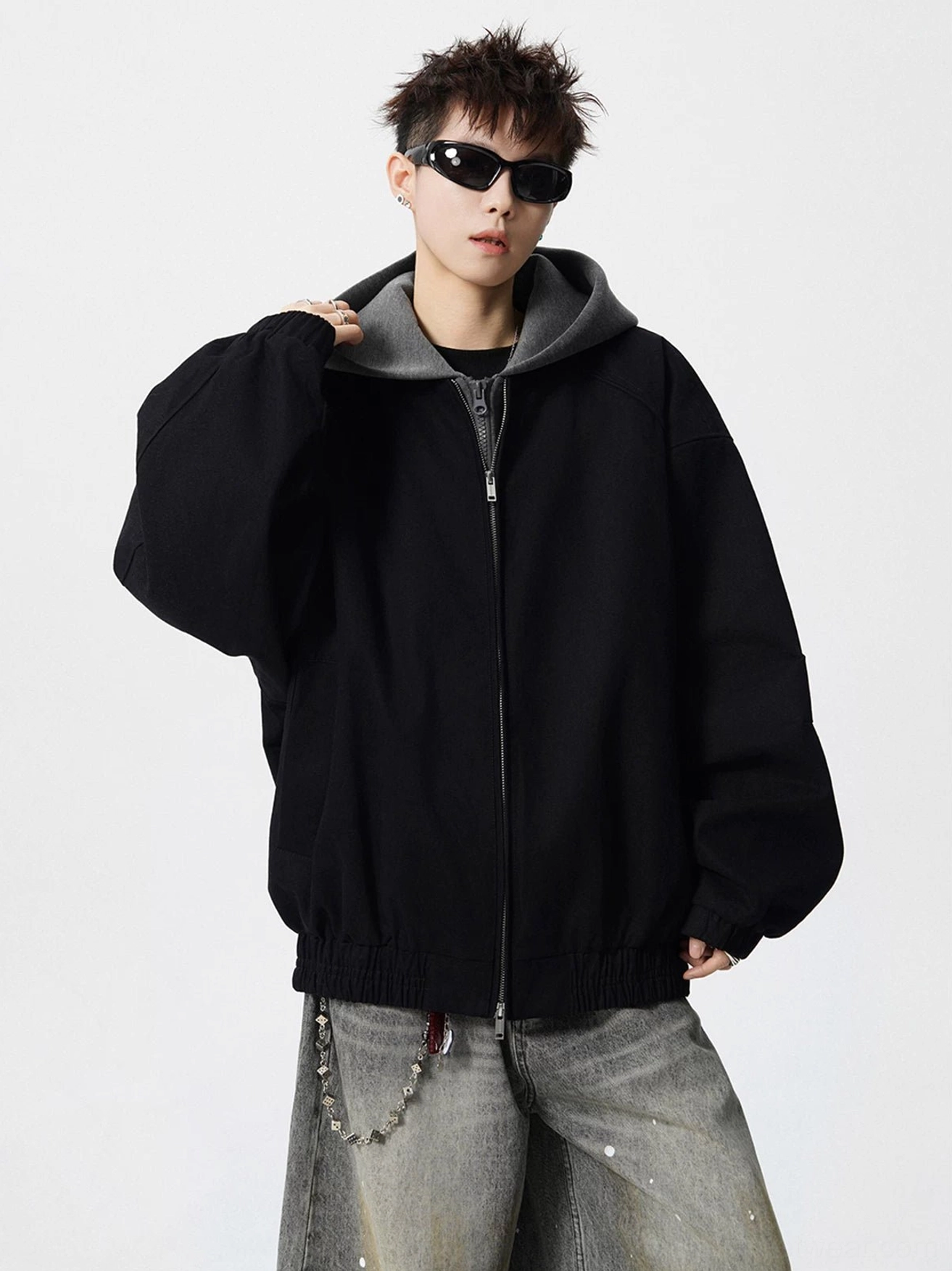 Front view of black oversized zip-up streetwear bomber jacket with contrasting grey layered hood