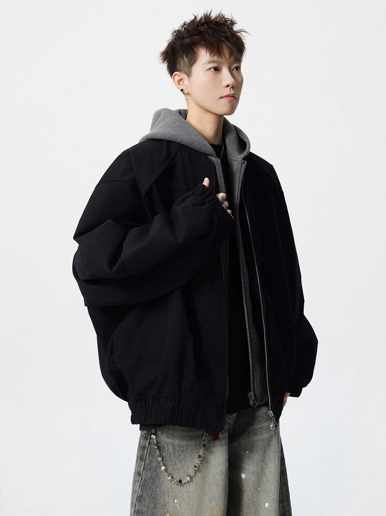 Black oversized layered hooded streetwear bomber jacket with grey hood detail shown in three-quarter front view