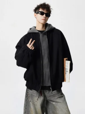 Oversized black and grey layered hood bomber jacket styled with splashed wide-leg jeans and chain accessory