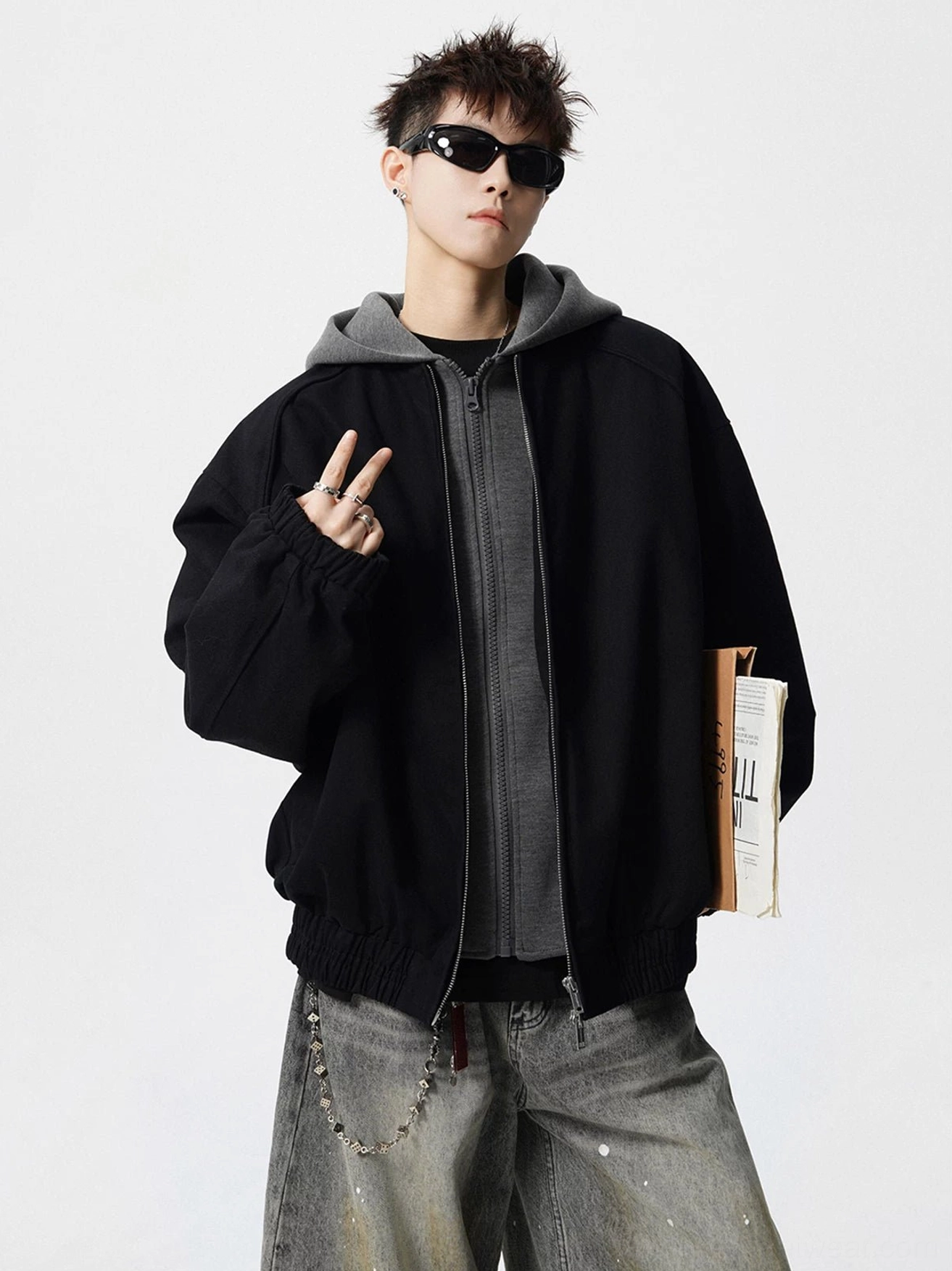 Oversized black and grey layered hood bomber jacket styled with splashed wide-leg jeans and chain accessory
