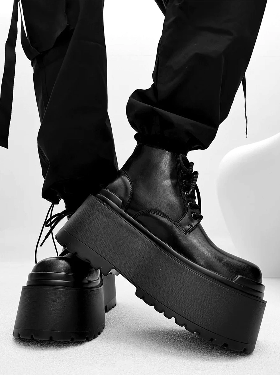 Black lace-up platform ankle boots with extra thick chunky sole worn with cropped black cargo pants
