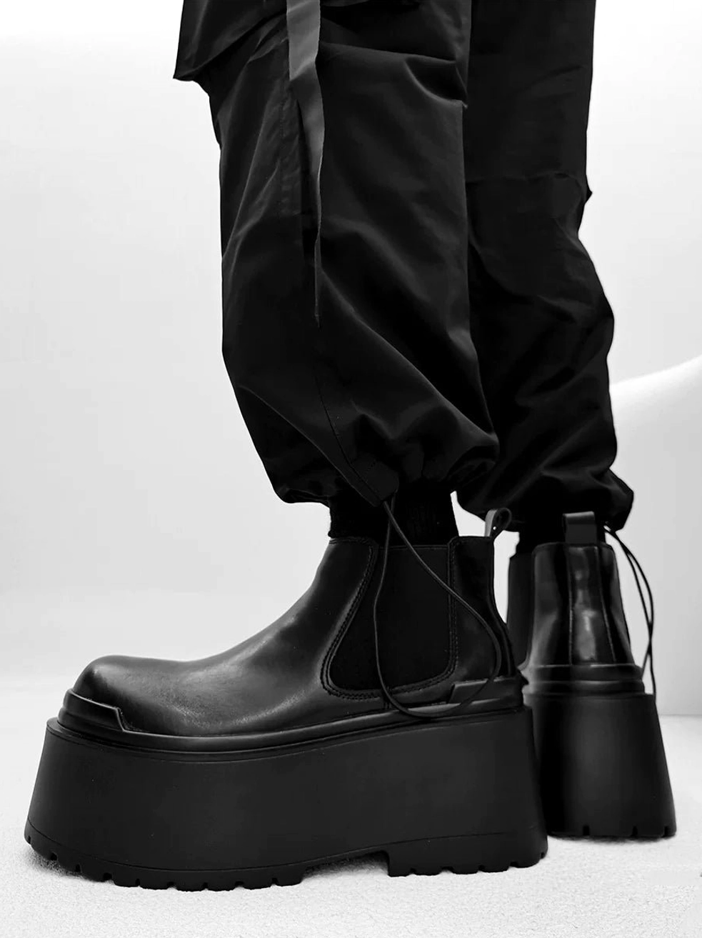Black lace-up platform boots rear side view with smooth leather upper heel pull tab and oversized rubber outsole
