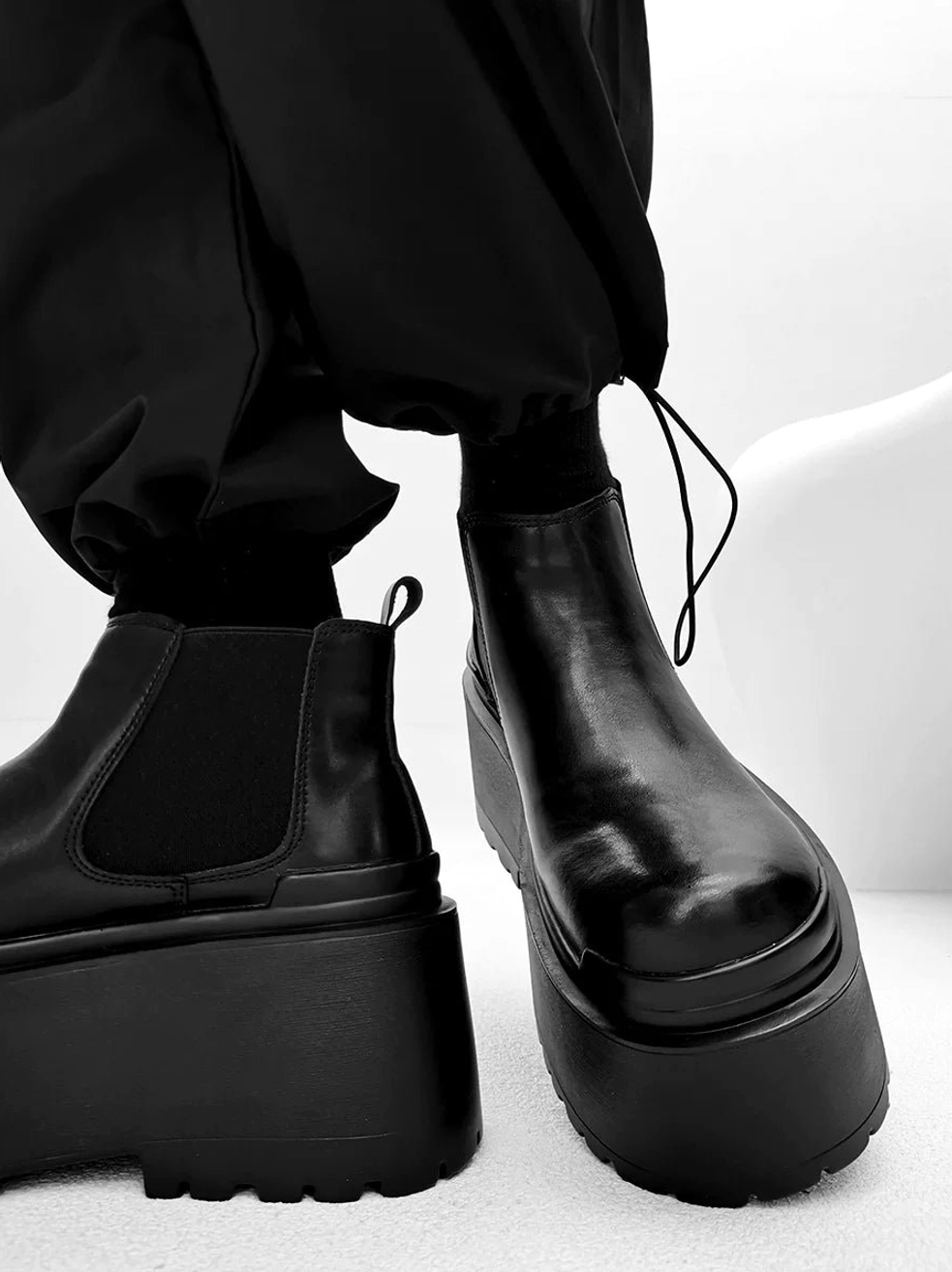 Rear three-quarter view of black platform Chelsea boots showing elastic side panels pull tab and deep tread sole