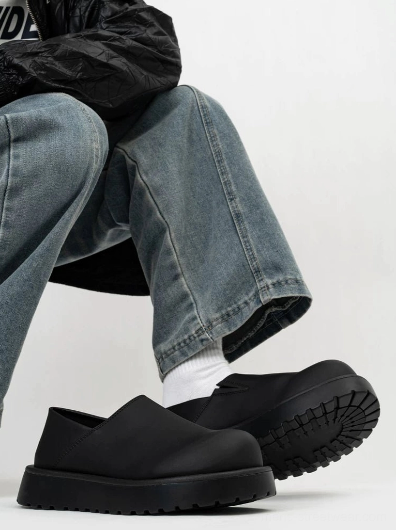 Matte black platform clogs worn with white socks and washed jeans showing thick anti-slip sole and low slip-on silhouette