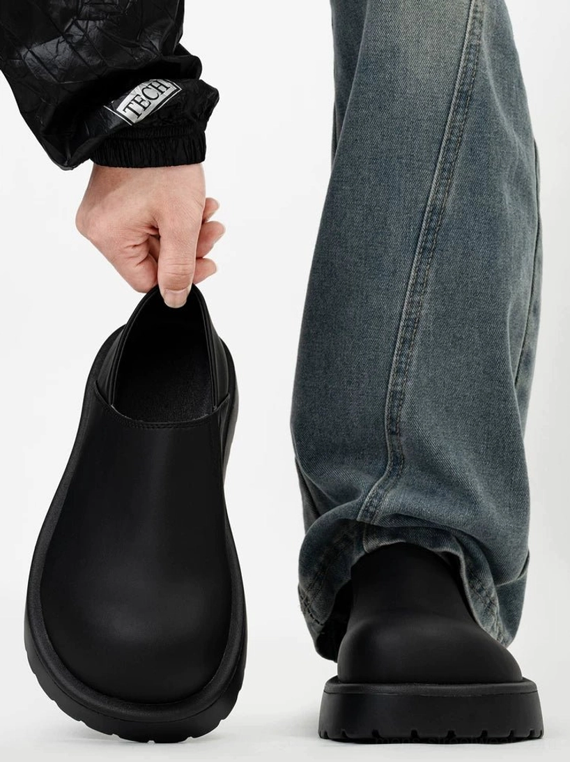 Front view of matte black platform slip-on clogs worn with washed denim in a minimalist Seoul streetwear look