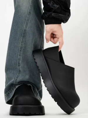 Matte black Midnight Monolith platform slip-on clogs shown from a low rear side angle with washed denim streetwear outfit