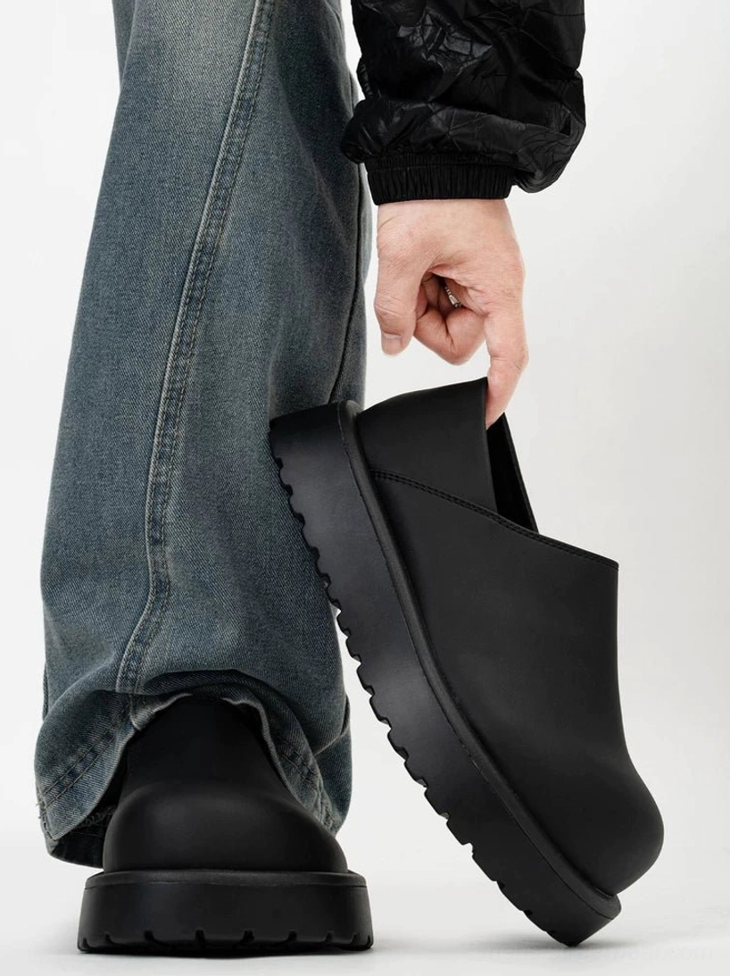 Matte black Midnight Monolith platform slip-on clogs shown from a low rear side angle with washed denim streetwear outfit