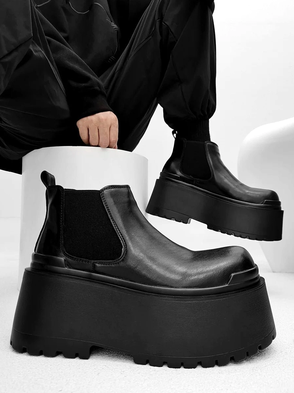 Black ultra platform Chelsea ankle boots with smooth leather upper and chunky rubber sole worn with black cargo pants