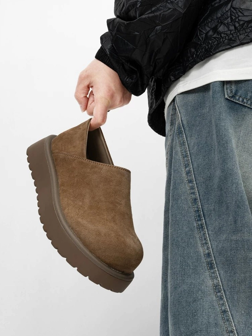 Brown suede-style Midnight Monolith platform slip-on clogs held in hand showing chunky rubber outsole and side profile