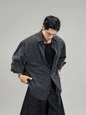 Black and white oversized pinstripe shirt with dropped shoulders, curved hem, side chain detail, and layered Korean streetwear styling