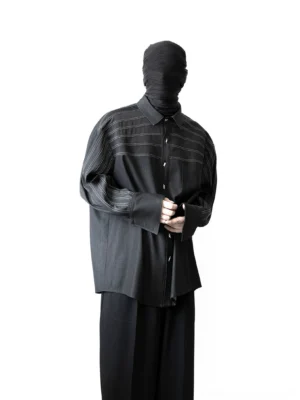 Front view of an oversized black stripe stitch shirt with contrast chest detailing, pleated long sleeves, and relaxed streetwear fit