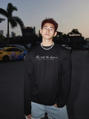 Front medium close-up of a black Midnight Reset Script long sleeve streetwear tee with white cursive chest graphic, relaxed fit, smooth jersey fabric, and classic crew neckline