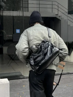 Midnight rivet faux leather streetwear crossbody tote bag worn on the back with grey bomber jacket