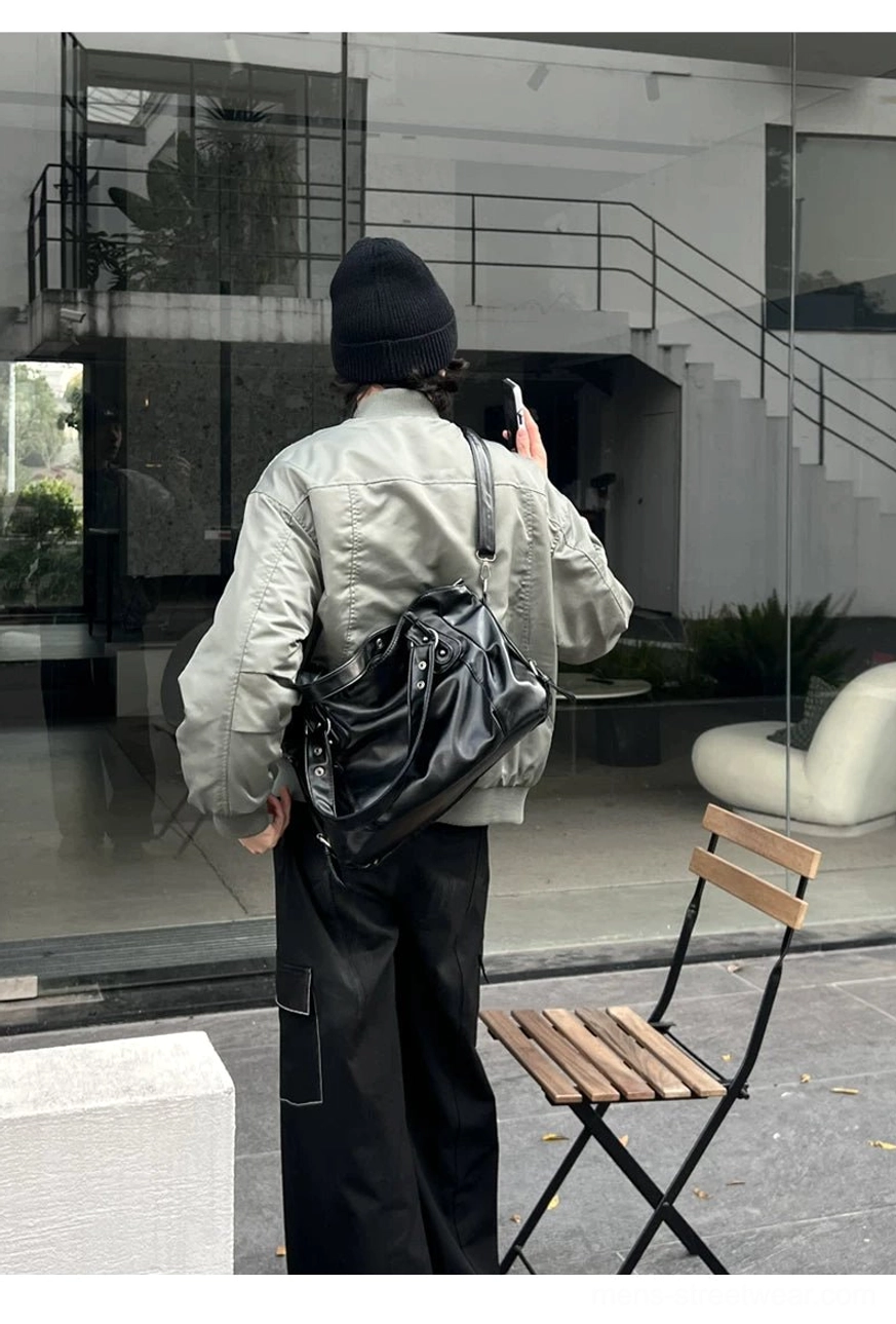 Midnight rivet black faux leather crossbody tote bag worn low on the hip in a casual city outfit