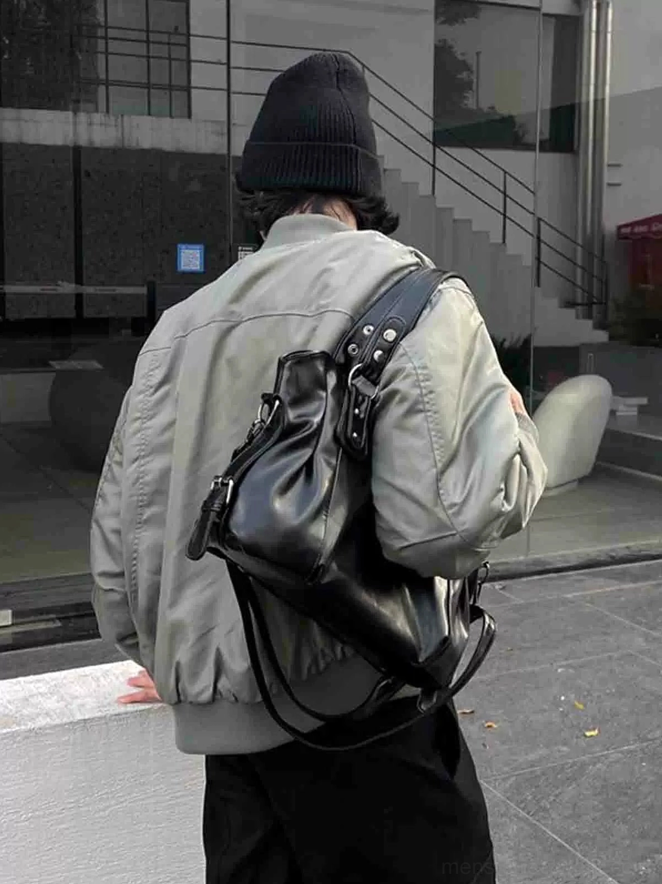 Midnight rivet oversized black faux leather tote bag worn with a grey flight jacket from the back