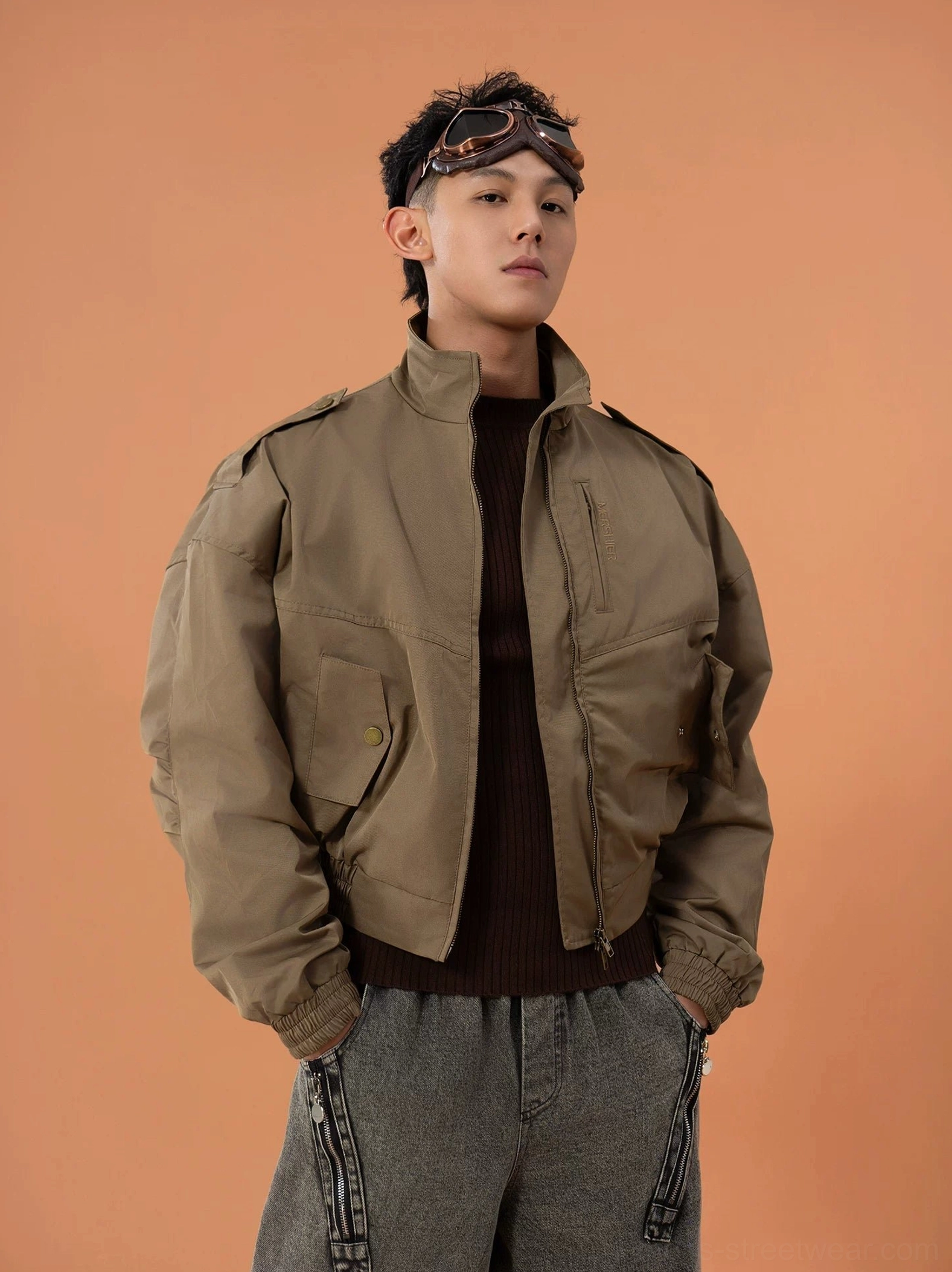 Oblique front view of a military green cropped bomber jacket worn open with visible chest snap pockets elasticated cuffs and relaxed streetwear fit