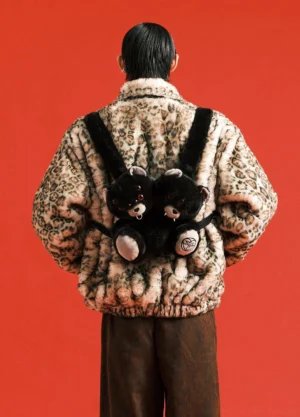 Black evil bear plush backpack styled on a model wearing a fuzzy leopard print jacket and brown trousers in a bold urban streetwear outfit