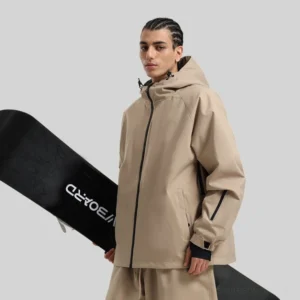 Tan hooded snowboard shell jacket shown from a front three-quarter angle on a male model holding a snowboard, featuring raglan sleeves and zippered pockets