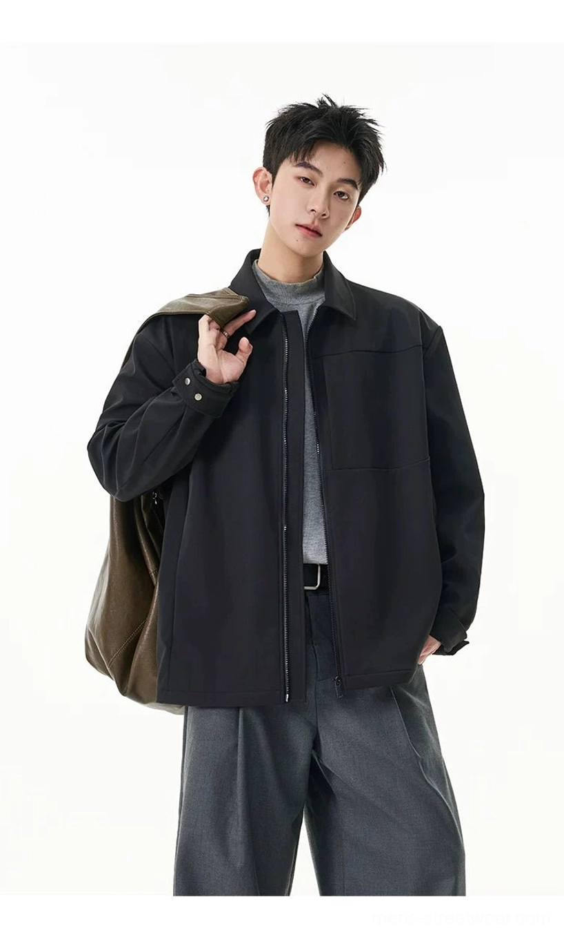 Three-quarter side view of men's black zip shirt jacket with adjustable cuffs styled with gray trousers and canvas bag