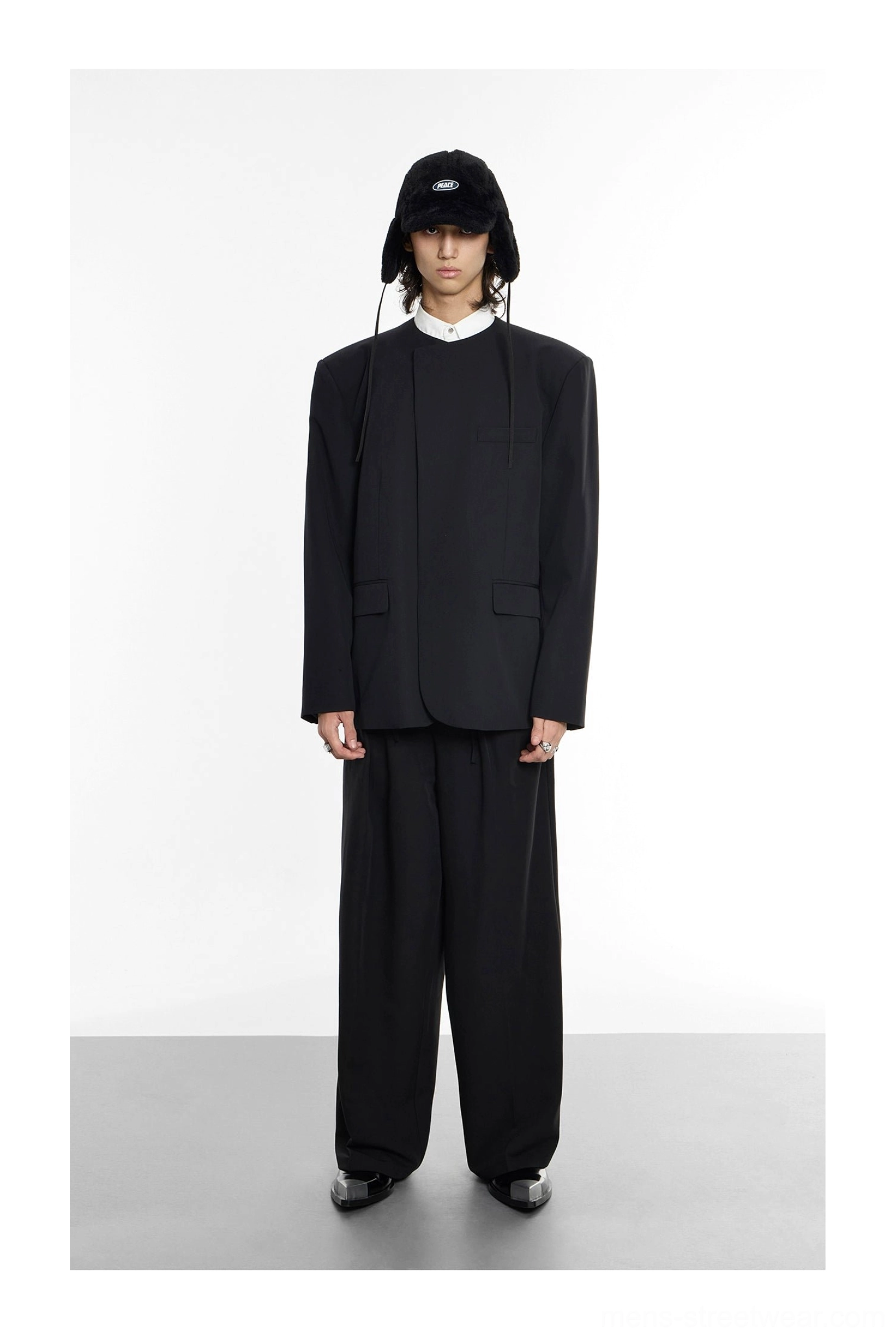 Full body view of minimalist black collarless oversized blazer styled with wide-leg trousers