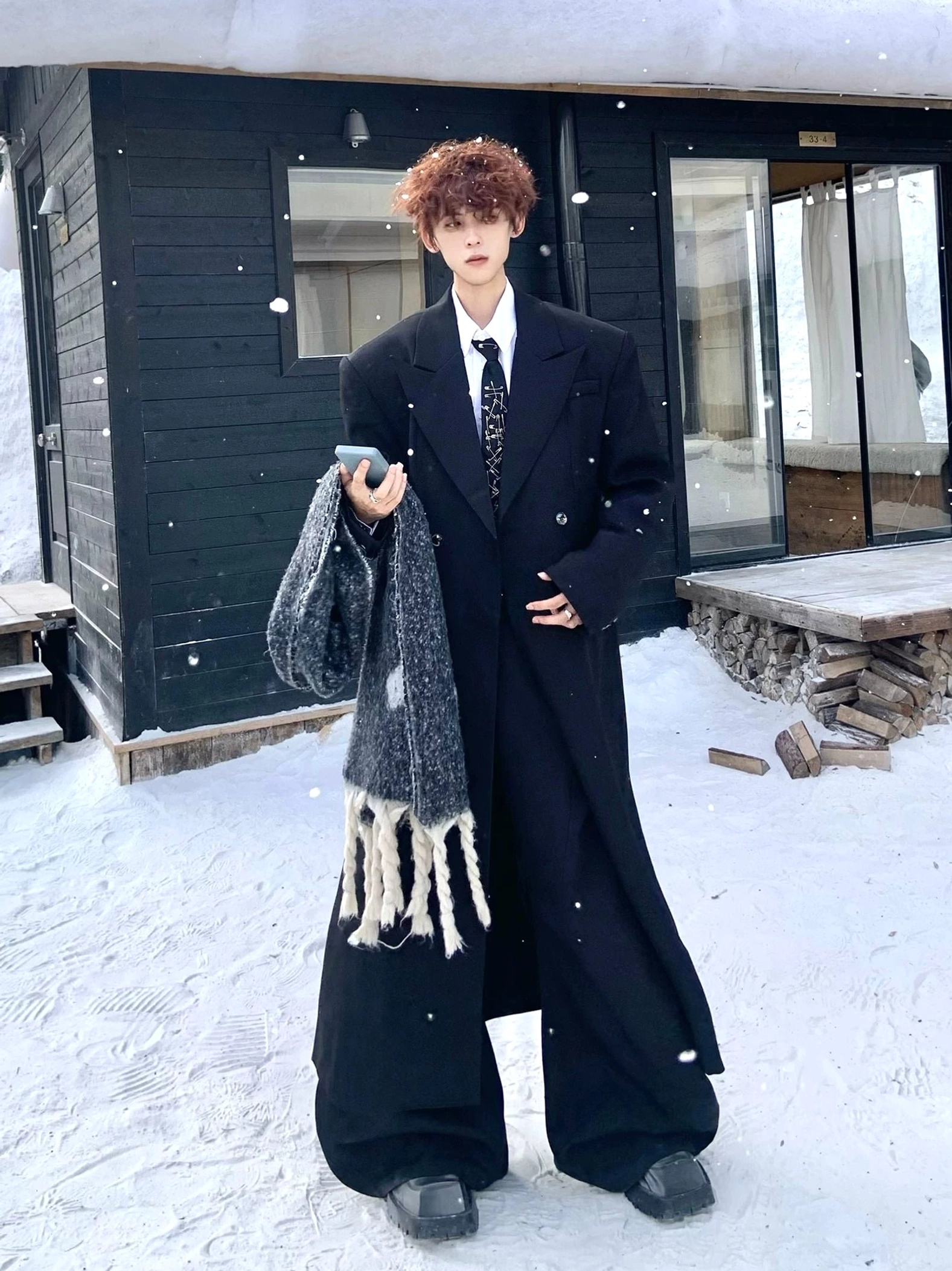 Minimalist black oversized double-breasted overcoat with structured shoulders in snowy outdoor setting