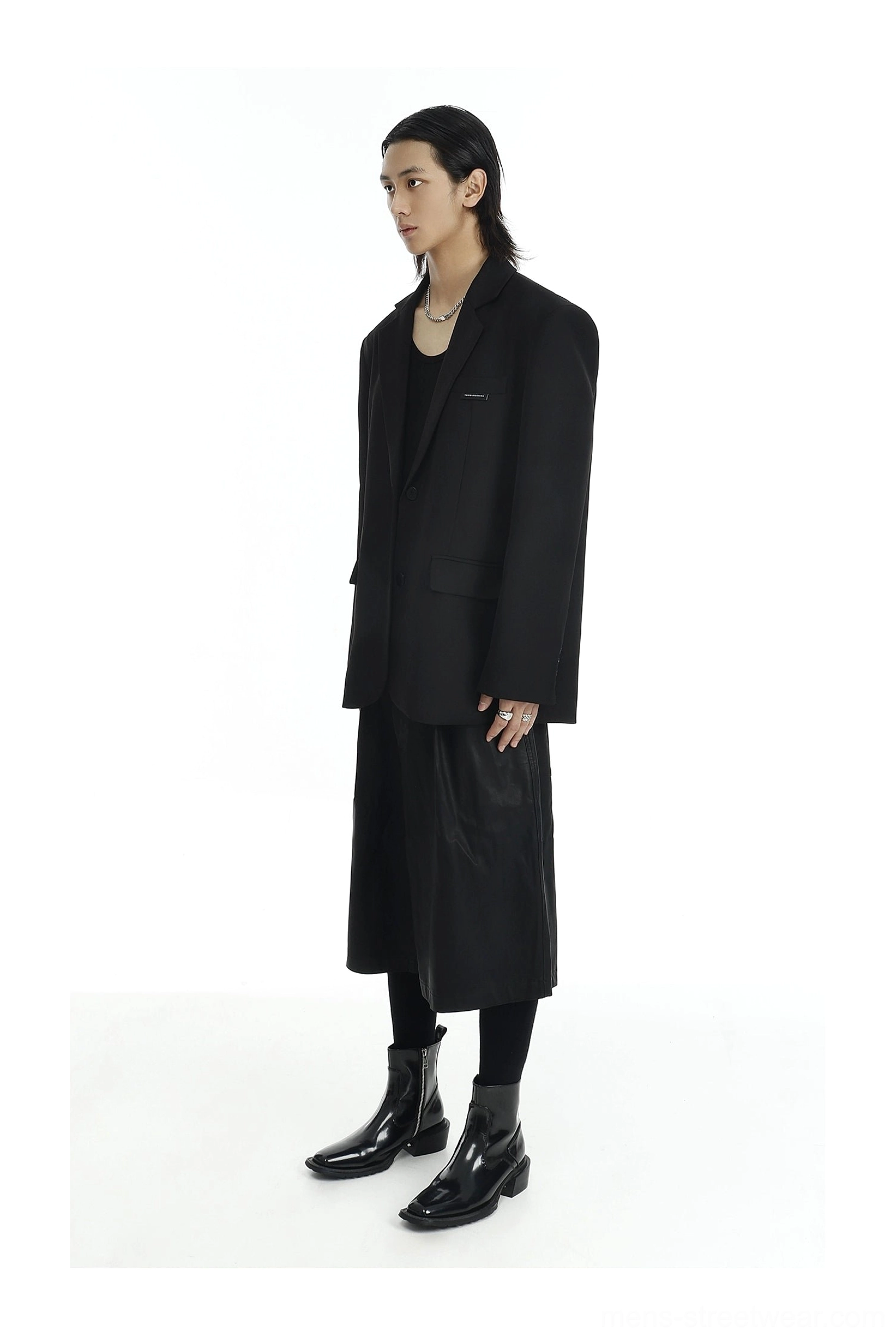 Minimalist black oversized two-button blazer styled with a midi skirt, black tights, and leather ankle boots
