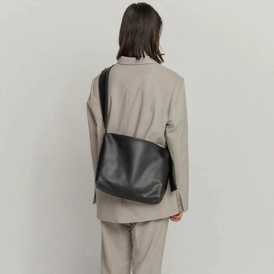Black minimalist PU leather tech sling bag full back view worn crossbody with gray tailored streetwear suit