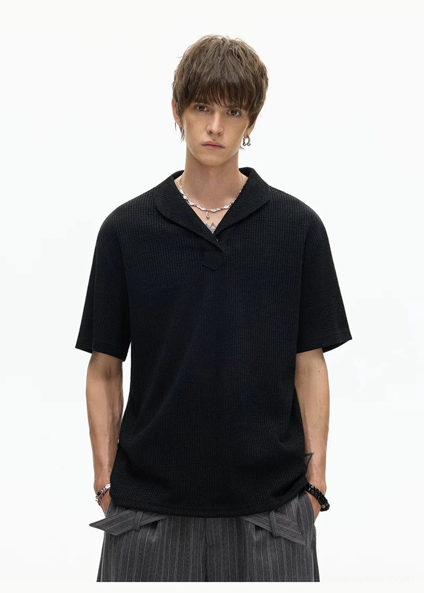 Front view of minimalist black shawl collar knit polo tee with short sleeves and relaxed boxy silhouette for everyday streetwear