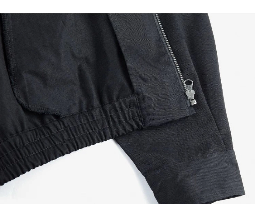 Minimalist Harrington jacket detail view showing structured cotton twill fabric, practical pockets, adjustable cuffs, and elasticated hem