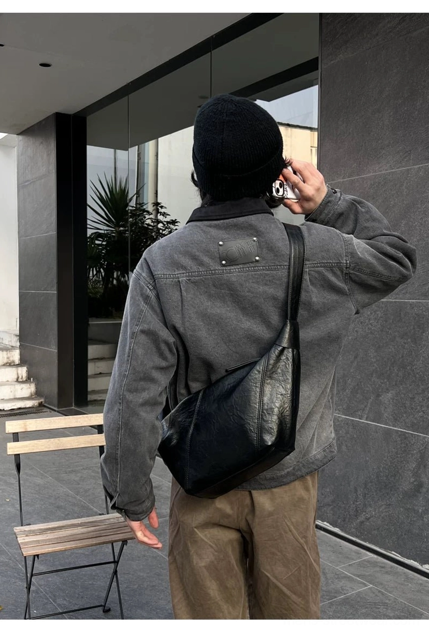 Black PU leather curved sling bag worn across the back with relaxed Korean inspired denim streetwear
