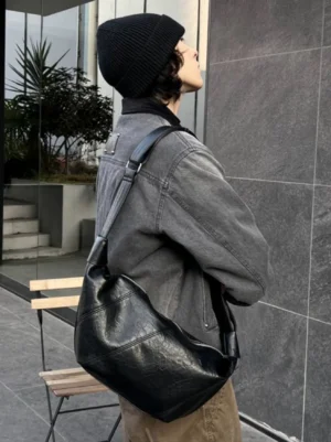 Black curved PU leather crossbody sling bag side rear view styled with gray denim Korean streetwear outfit