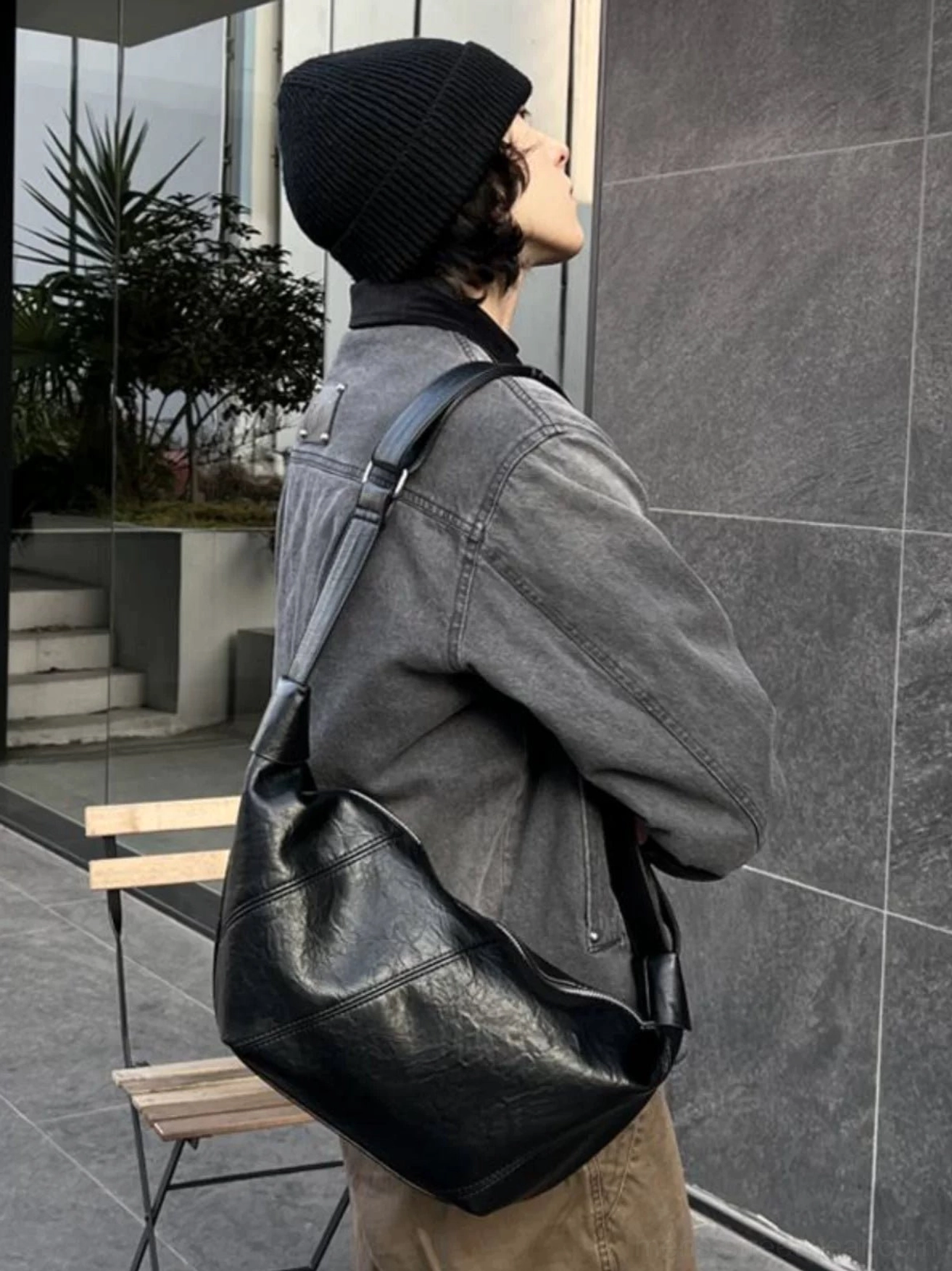 Black curved PU leather crossbody sling bag side rear view styled with gray denim Korean streetwear outfit