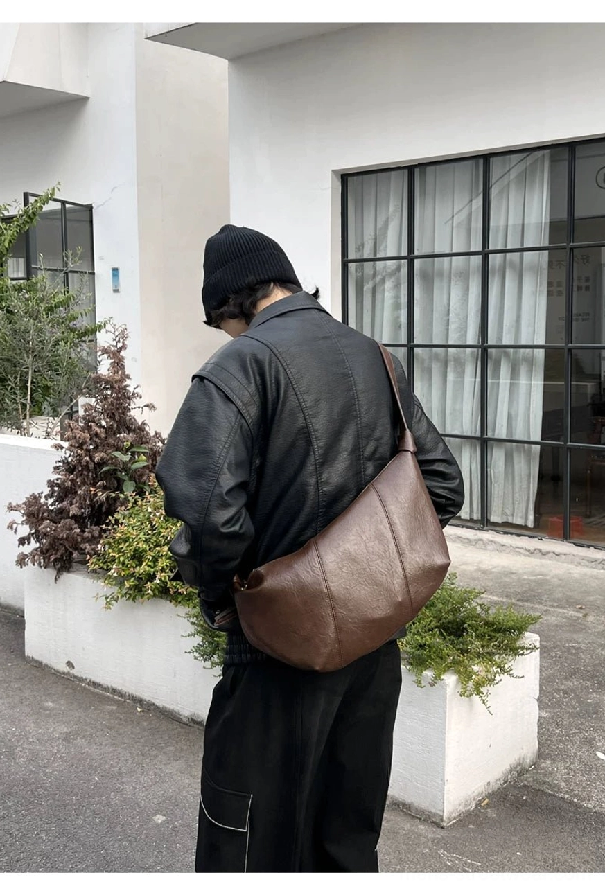 Coffee brown minimalist curved PU leather crossbody sling bag with relaxed streetwear silhouette
