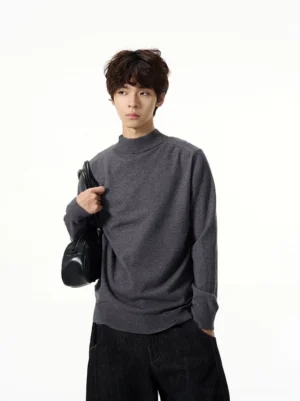 Dark gray minimalist mock neck knit sweater worn by male model in Seoul streetwear outfit with black jeans and shoulder bag front view