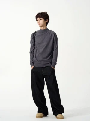Dark gray relaxed fit mock neck knit sweater side view styled with wide leg black jeans and casual shoes