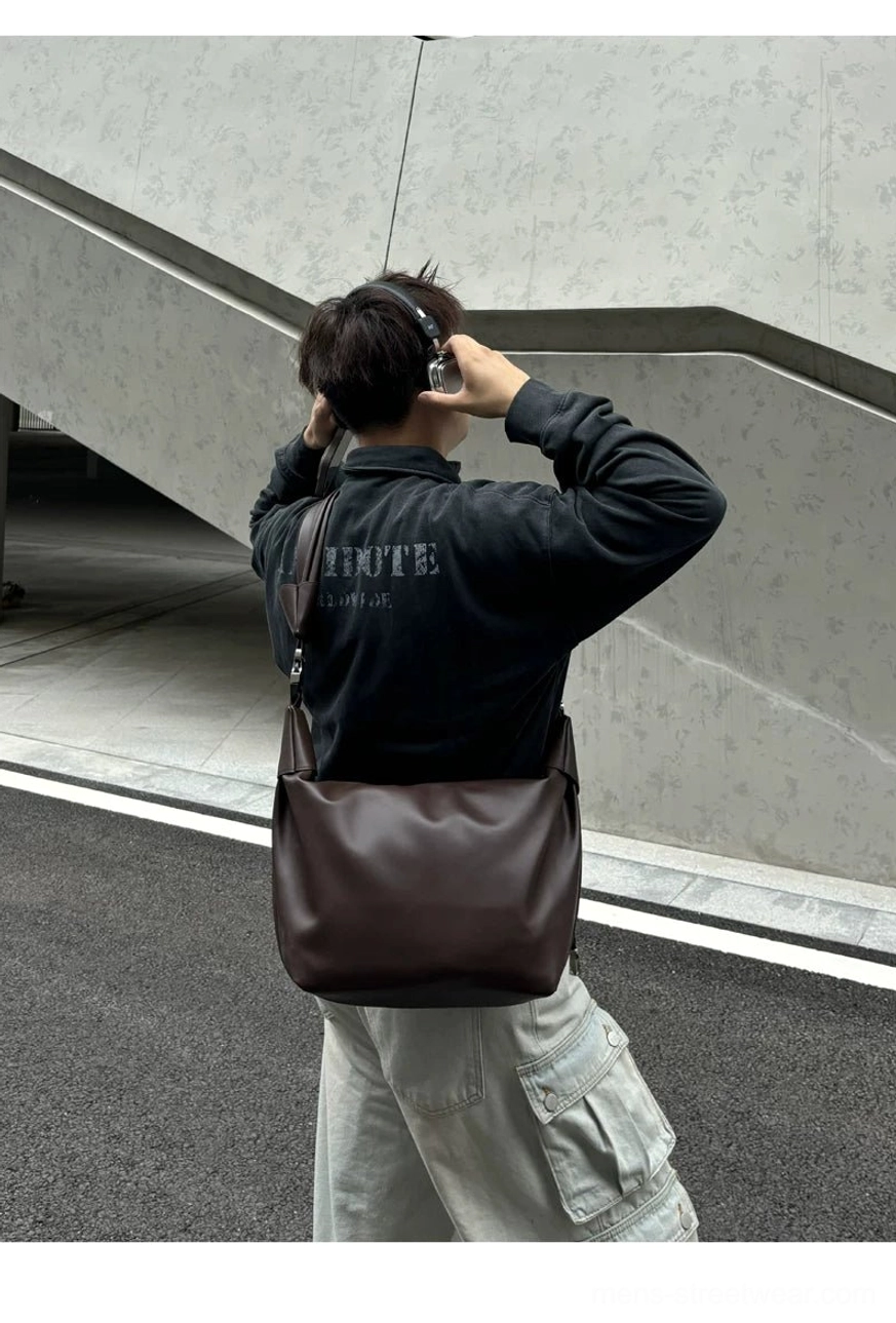 Dark brown semi-matte PU leather shoulder sling bag hanging naturally at the side in streetwear styling