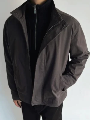 Brown Korean streetwear stand collar jacket with concealed zip placket worn by male model in minimalist studio
