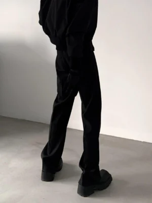 Black minimalist straight-leg tailored trousers rear low-angle view with draped hem over chunky platform shoes