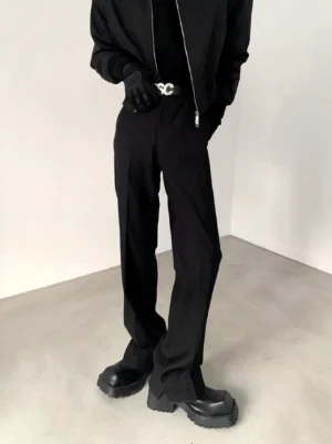 Black straight-leg tailored trousers styled with cropped jacket gloves silver buckle belt and platform boots