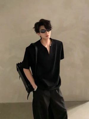 Male model wearing a black minimalist V-notch neck short sleeve shirt with wide-leg trousers and shoulder bag in a clean Korean streetwear studio look