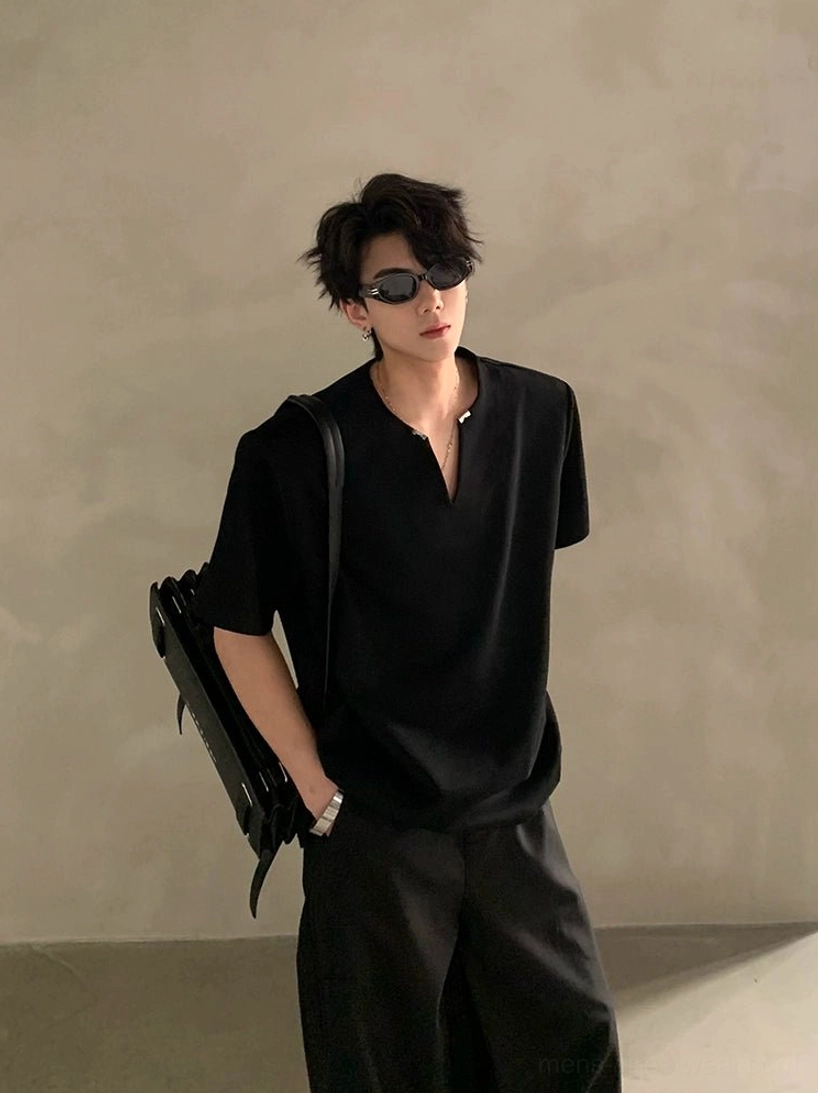 Male model wearing a black minimalist V-notch neck short sleeve shirt with wide-leg trousers and shoulder bag in a clean Korean streetwear studio look