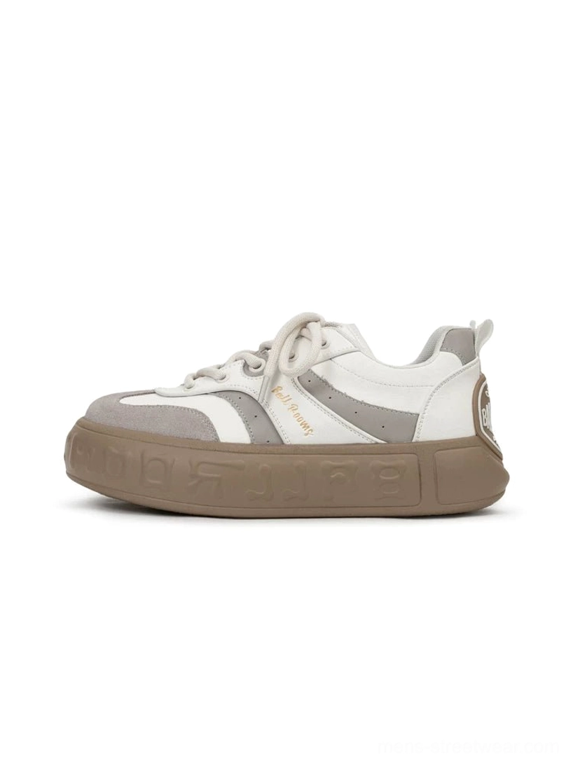 Minimalist white and gray chunky casual sneakers with suede toe cap subtle upper lettering and embossed gum outsole shown on a studio background