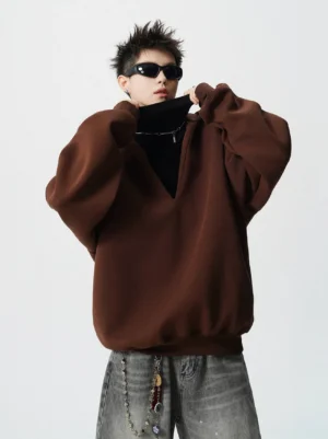 Back three-quarter view of a deep brown oversized hooded sweatshirt with ribbed hem and cuffs styled with a black inner layer and waist chain