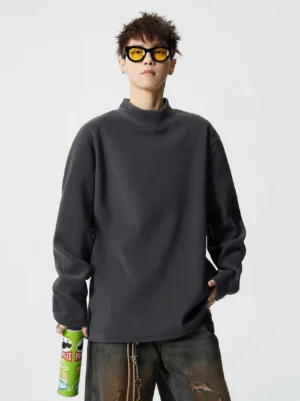 Dark grey boxy mock neck fleece streetwear top styled with baggy denim and yellow tinted sunglasses